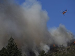 A helicopter flies over a wildfire Thursday, Oct. 12, 2017, near Calistoga, Calif. Officials say progress is being made in some of the largest wildfires burning in Northern California but that the death toll is almost sure to surge. (AP Photo/Jae C. Hong)