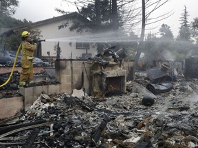 Napa City firefighter Hattie Borg hoses down a fire-ravaged home Monday, Oct. 9, 2017, in Napa, Calif. (AP Photo/Marcio Jose Sanchez)