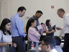 In this Thursday, Aug. 24, 2017, photo, Phil Wiggett, right, a recruiter with the Silicon Valley Community Foundation, looks at a resume during a job fair in San Jose, Calif. On Friday, Oct. 6, 2017, the U.S. government issues the September jobs report. (AP Photo/Marcio Jose Sanchez)