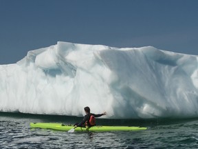Fogo Island, Newfoundland:  July 14 2017 - Olympic gold medal kayaker Adam van Koeverden touches and iceberg as he paddle bye on day 3 of the fifth leg of the Canada C3 expedition in Fogo Island, Newfoundland, July 14, 2017.