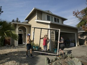 Chris Alejos, left, and his wife, Brittany, get help from friend Nick Cann as they remove a bed frame from their home in the Coffey Park area of Santa Rosa, Calif. Monday, Oct. 16, 2017. The Alejos home was not damaged by the fire that destroyed homes all around theirs, but smoke damage and no power made it unlivable for now. (AP Photo/Rich Pedroncelli)
