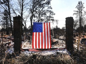 On Willowview Court in Santa Rosa, Calif., a homeowner displays an American flag amidst the destruction from a wildfire, Thursday Oct. 12, 2017. Since igniting Sunday in spots across eight counties, the fires have transformed many neighborhoods into wastelands. Thousands of homes and businesses have been destroyed and thousands of people were forced to flee. (Kent Porter/The Press Democrat via AP)