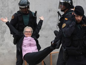 An elderly woman is removed by force as police move in on the crowds at a polling station where Catalonia President Carles Puigdemont was to vote  on October 1, 2017 in Sant Julia de Ramis, Spain.
