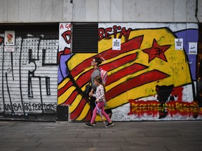 Catalans go about their daily business in the Vila de Gracia district ahead of Tuesday's parliamentary announcement.