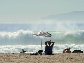 Whittier resident Ken Harrison relaxes at the beach during record heat in Huntington Beach, Calif., Monday, Oct. 23, 2017.  Records fell as temperatures soared into triple digits across Southern California on Monday and authorities warned of more dangerous heat plus gusty Santa Ana winds that boost the risk of wildfires. (Ken Steinhardt/Los Angeles Daily News via AP)