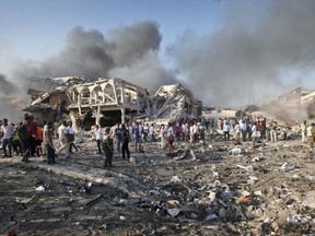 FILE - In this Oct. 14, 2017, file photo, Somalis gather and search for survivors by destroyed buildings at the scene of a huge explosion in the capital Mogadishu, Somalia. Countless members of Somalia's vast diaspora have returned to Somalia in recent years to help rebuild their homeland after decades of civil war. Some who spoke to The Associated Press say they won't be deterred by the Oct. 14 bombing that killed more than 300. Instead, they say the attack marks a turning point, and is a call for all Somalis to work toward peace. (AP Photo/Farah Abdi Warsameh, File)