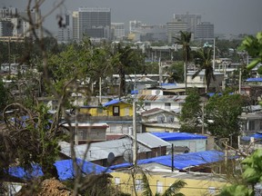In this Oct. 19, 2017 photo, homes stand covered with FEMA tarps in the Cantera area, as the banking zone stands in the background in San Juan, Puerto Rico. Puerto Rico has some of the highest income inequality in the world, according to Jose Caraballo, president of Puerto Rico Economists Association. (AP Photo/Carlos Giusti)