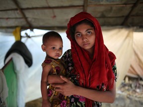 A Rohingya woman holds her child and stands for a photograph at a makeshift camp near Kutupalong refugee camp in Cox's Bazar, Bangladesh, Tuesday, Oct. 3, 2017. More than half a million Rohingya have fled from Myanmar to Bangladesh in just over a month, the largest refugee crisis to hit Asia in decades. The current exodus is in addition to hundreds of thousands of Rohingya who fled prior violence in Myanmar, where the Muslim ethnic group has faced decades of persecution and discrimination in the Buddhist-majority nation. (AP Photo/Zakir Hossain Chowdhury)