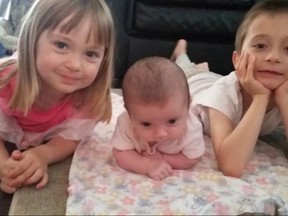 Jack Skrt, right, poses with his younger sisters Emily, 3, left, and Leah, three-months-old, in July 2017. An Ontario family has launched a human rights complaint against a school board in an effort to get a popular form of therapy for autistic children provided to their son in class. THE CANADIAN PRESS/HO - Beth Skrt