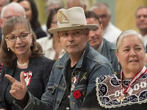 Tragically Hip lead singer Gord Downie raises his arm in response to a speaker as he sits with Sylvia Maracle, right, and Jacqueline Guest during an investiture ceremony, in Ottawa on Monday, June 19, 2017. As Gord Downie fans reflect on his music and advocacy for the plight of Canada's Indigenous people, the medical community is also remembering his great contributions in that world that they say will be felt for decades to come. THE CANADIAN PRESS/Adrian Wyld