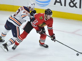 Chicago Blackhawks' Lance Bouma (17) reaches for the puck as Edmonton Oilers' Ryan Nugent-Hopkins defends during the third period of an NHL hockey game Thursday, Oct. 19, 2017, in Chicago. Edmonton won 2-1 in overtime. (AP Photo/Paul Beaty)