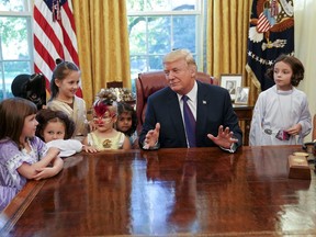 President Donald Trump talks with Claire Thomas, 5, far left, from Washington, before passing out candy to children dressed in their Halloween costumes in the Oval Office of the White House, Friday, Oct. 27, 2017. The White House had invited the children of members of the media to visit the president and to trick-o-treat on the White House complex of the Eisenhower Executive Office building. (AP Photo/Pablo Martinez Monsivais)