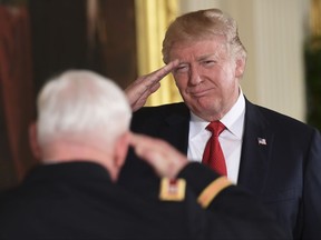 President Donald Trump, right, salutes retired Army Capt. Gary M. Rose, left, before bestowing him with the nation's highest military honor, the Medal of Honor, during a ceremony in the East Room of the White House in Washington, Monday, Oct. 23, 2017. (AP Photo/Susan Walsh)