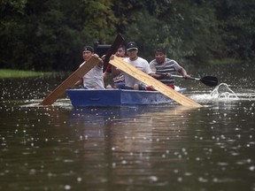 People use plywood to row a boat down Deats Road in Dickinson, Texas on Aug. 28, 2017, as floodwaters from Hurricane Harvey rise.