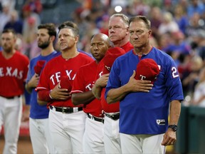 FILE- In this Thursday, Sept. 28, 2017, file photo, Texas Rangers manager Jeff Banister, right, staff and players stand during the playing of the national anthem before a baseball game against the Oakland Athletics in Arlington, Texas. (AP Photo/Tony Gutierrez, File)