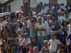 A Bangladeshi police man stands guard as Rohingya Muslims, who crossed over from Myanmar into Bangladesh, wait for the arrival of Queen Rania of Jordan, at Kutupalong refugee camp, Bangladesh, Monday, Oct. 23, 2017. More than 580,000 refugees have arrived in Bangladesh since Aug. 25, when Myanmar security forces began a scorched-earth campaign against Rohingya villages. Myanmar's government has said it was responding to attacks by Muslim insurgents, but the United Nations and others have said the response was disproportionate. (AP Photo/Dar Yasin)