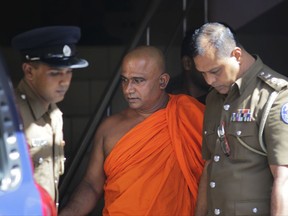 Sri Lankan hardliner Buddhist monk Akmeemana Dayarathana, center, escorted by police officers is being produce at a local court in Colombo, Sri Lanka, Monday, Oct. 2, 2017. Buddhist monk was arrested over the allegations of threatening a group of Rohingya refugees who were residing in a UN run safe house last week. (AP Photo/Eranga Jayawardena)