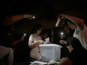 FILE, In this Sunday, Oct. 1, 2017 file photo, volunteers, acting as polling station officials, start to count ballots during a blackout after the polling station closed at the La Llacuna school in the Poble Nou neighborhood in Barcelona, Spain. The ballot boxes arrived from France in the dead of night, were stored in homes and improvised hidey-holes, and then secretly shuttled to polling stations across Catalonia right under the nose of police. (AP Photo/Manu Fernandez, File)