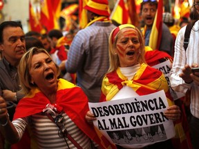 Demonstrators shout slogans, some of them holding a banner reading in Catalan "disobedience to the bad government", as they gather near a headquarters of federal police in Barcelona, Spain, Sunday Oct. 8, 2017. Demonstrators gathered early in Barcelona on Sunday ahead of a march to show support for the Spanish union and call on Catalonia not to declare independence. (AP Photo/Francisco Seco)