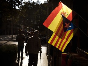 People walk past a Spanish and an estelada, or independence flag, hanging up for sale in a shop in Barcelona, Spain, Wednesday, Oct. 11, 2017