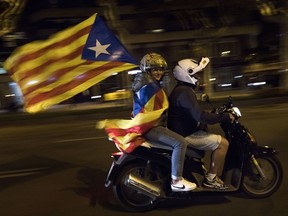 A woman holds an estelada or independence flag on a motorcycle after taking part on a protest against the National Court's decision to imprison civil society leaders without bail, in Barcelona, Spain, Tuesday, Oct. 17, 2017. Protesters were gathering for a fresh round of demonstrations in Barcelona Tuesday to demand the release of two leaders of Catalonia's pro-independence movement who were jailed in a sedition probe. (AP Photo/Emilio Morenatti)