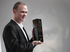 Britain's Chris Froome, centre, poses with his Velo d'Or award during the presentation of the 2018 Tour de France cycling race, in Paris, Tuesday Oct. 17, 2017. The 105th edition of the race starts on July 7 2018 to end on the Champs-Elysees avenue on July 29. French former cyclist Bernard Hinault stands at right. (AP Photo/Christophe Ena)