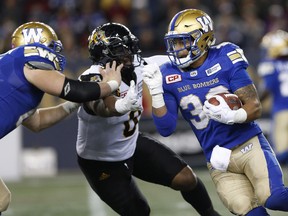 Winnipeg Blue Bombers RB Andrew Harris (right) rushes upfield against the Hamilton Tiger-Cats on Oct. 6.