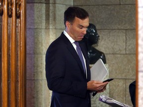 Finance Minister Bill Morneau stops to look at his cell phone as he makes his way into the House of Commons to deliver the fall economic update in Tuesday, October 24, 2017 in Ottawa.