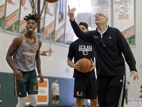 Miami head coach Jim Larranaga, right, tosses the ball as Lonnie Walker, left, looks on, Monday, Oct. 23, 2017, during an NCAA basketball media day practice, in Coral Gables, Fla. (AP Photo/Alan Diaz)