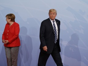 FILE - In this July 7, 2017 file photo U.S. President Donald Trump walks off after being greeted by German Chancellor Angela Merkel after arriving at the G20 Summit in Hamburg, Germany. Several prominent German foreign policy experts are urging the incoming German government not to turn away from the United States despite U.S. President Donald Trump's unilateral "America First" stance. (AP Photo/Evan Vucci, file)