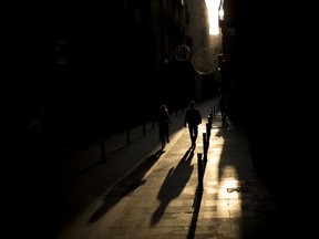 The sun casts long shadows as poeple walk along a street in downtown Barcelona, Spain, Monday Oct. 30, 2017. (AP Photo/Francisco Seco)