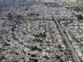 FILE - In this Oct. 14, 2017 file photo, an aerial view shows the devastation of the Coffey Park neighborhood after a wildfire swept through it in Santa Rosa, Calif. CalFire spokesman Daniel Berlant said Monday, Oct. 23, 2017, the estimate of homes and structures destroyed was boosted from 6,900 late last week to 8,400 as officials neared completion of their damage assessment. (AP Photo/Marcio Jose Sanchez, File)