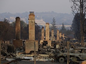 FILE - In this Oct. 13, 2017 file photo, a row of chimneys stand in a neighborhood devastated by a wildfire near Santa Rosa, Calif. CalFire spokesman Daniel Berlant said Monday, Oct. 23, 2017, the estimate of homes and structures destroyed was boosted from 6,900 late last week to 8,400 as officials neared completion of their damage assessment. (AP Photo/Jae C. Hong, File)