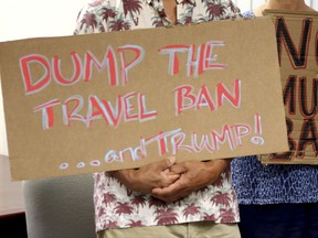 FILE- In this June 30, 2017, file photo, critics of President Donald Trump's travel ban hold signs during a news conference in Honolulu. The Trump administration is appealing a Hawaii judge's order that blocks the newest version of the travel ban. Attorneys for the U.S. government filed court papers Tuesday, Oct. 24, 2017, saying they are taking the case to the 9th U.S. Circuit Court of Appeals. The appeals court has blocked both of Trump's previous bans. (AP Photo/Caleb Jones, File)
