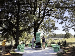 In this Friday, Oct. 20, 2017 photo, a monument to honor African-Americans who were buried in unmarked graves in the previously segregated Alta Vista Cemetery is wrapped by workers Tommy Casper, left, and Kevin Towe after being displayed for a photo in Gainesville, Ga. The previously unmarked graves of more than 1,100 black souls buried in the cemetery will be honored with a memorial to be dedicated Sunday. Recently, the city discovered the extent of the unmarked graves using ground-penetrating radar. (AP Photo/David Goldman)