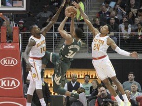 Milwaukee Bucks forward Giannis Antetokounmpo (34) tries to score as Atlanta Hawks center Dewayne Dedmon (14) and forward Kent Bazemore (24) close in on him during the first half of an NBA basketball game, Sunday, Oct. 29, 2017, in Atlanta. (AP Photo/John Amis)