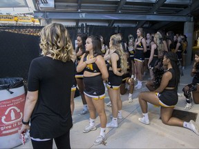 Four of the five Kennesaw State cheerleaders who took a knee three weeks ago during the Kennesaw State football game, take a knee once again out of sight of the fans under the visitors' bleachers, during the national anthem before an NCAA college football game between Kennesaw State and Gardner-Webb, Saturday, Oct. 21, 2017, in Kennesaw, Ga. The cheerleaders are kneeling in protest police brutality. (Kelly J. Huff/The Marietta Daily Journal via AP)