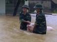 Two soldiers walk a pig through flood water in northern province of Thanh Hoa, Vietnam, Wednesday, Oct. 11, 2017. Floods triggered by a tropical depression in Vietnam have killed 15 people and left eight others missing. The storm hit central Vietnam on Tuesday, bringing heavy rain to the region and to parts of northern Vietnam. (Trinh Duy Hung/Vietnam News Agency via AP)