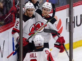 New Jersey Devils defenceman John Moore, left, celebrates his game winning goal in overtime against the Senators with teammates Nico Hischier, right, and Taylor Hall in Ottawa on Thursday night.