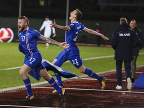 Iceland's players, Aron Einar Gunnarsson, left and Jon Dadi Bodvarsson celebrate their team's victory against Kosovo, following the World Cup Group I qualifying soccer match between Iceland and Kosovo in Reykjavik, Iceland, Monday Oct. 9, 2017. (AP Photo/Brynjar Gunnarsson).
