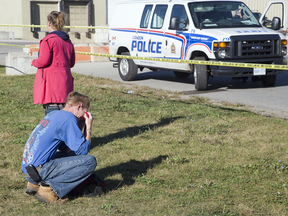 A friend wipes away tears outside the home where Raymond Beaver was killed during a home invasion in London, Ont. shortly before midnight on Oct. 2, 2017.