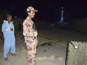 Pakistani security personnel stand guard at the site of a blast in Jhal Magsi, about 400 kilometers (240 miles) east of Quetta, Pakistan, Thursday, Oct. 5, 2017. A suicide bomber struck a Shiite shrine packed with worshippers in a remote village in southwestern Pakistan on Thursday, killing many people and leaving at least 25 wounded, a provincial government spokesman and the police said. (AP Photo/Ayub Khosa)