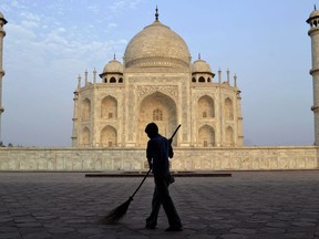 FILE- In this June 3, 2013 file photo, a worker sweeps in front of Taj Mahal in Agra, India. India's famed monument of love, the white marble Taj Mahal, is finding itself at the heart of a political storm with some members of India's ruling Hindu right-wing party claiming that the mausoleum built by a Muslim emperor does not reflect Indian culture. (AP Photo/Pawan Sharma, file)