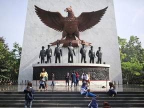 In this Sunday, Oct. 15, 2017, photo, visitors take photos taken near the statues of the seven Army officers who were killed in an abortive coup in 1965 that the military blamed on Indonesia's Communist Party and subsequently led to the anti-communist purge in 1965-1966, at Pancasila Sakti Monument in Jakarta, Indonesia. Declassified files have revealed new details of American government knowledge and support of an Indonesian army extermination campaign that killed several hundred thousand civilians during anti-communist hysteria in the mid-1960s. (AP Photo/Dita Alangkara)