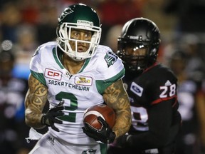 Saskatchewan Roughriders' Chad Owens, left, runs the ball past Calgary Stampeders' Brandon Smith during first half CFL football action in Calgary, Friday, Oct. 20, 2017.THE CANADIAN PRESS/Jeff McIntosh