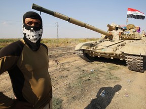 A member of the Iraqi forces stands next to a tank as an army convoy drives towards Kurdish peshmerga positions on the southern outskirts of Kirkuk on October 15, 2017.