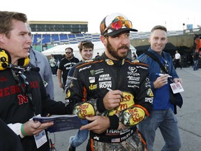 Martin Truex Jr. ,center, signs autographs winning the pole for Sunday's NASCAR Cup Series auto race at Kansas Speedway in Kansas City, Kan., Friday, Oct. 20, 2017. (AP Photo/Colin E. Braley)