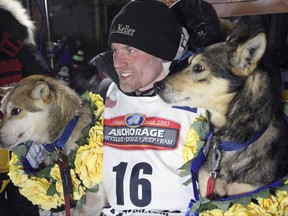 FILE - In this March 15, 2016, file photo, Dallas Seavey poses with his lead dogs Reef, left, and Tide after finishing the Iditarod Trail Sled Dog Race in Nome, Alaska. Seavey won his third straight Iditarod, for his fourth overall title in the last five years. Four-time Iditarod champion Dallas Seavey denies he administered banned drugs to his dogs in this year's race, and has withdrawn from the 2018 race in protest. The Iditarod Trail Committee on Monday identified Seavey as the musher who had four dogs test positive for a banned opioid pain reliever after finishing the race last March in Nome. (AP Photo/Mark Thiessen, File)