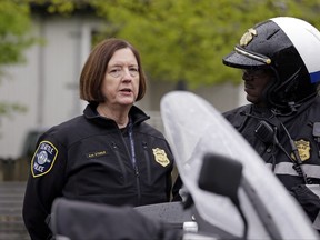 FILE - In this May 1, 2017 file photo, Seattle Police Chief Kathleen O'Toole, left, talks with an officer before a march for worker and immigrant rights at a May Day event in Seattle. In a court filing Friday, Oct. 13, 2017, the U.S. Justice Department said the city has eliminated the pattern of unconstitutional policing that resulted in federal authorities stepping in. (AP Photo/Elaine Thompson, File)