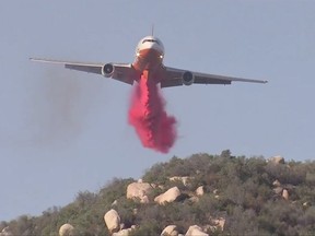 In this Friday, Oct. 27, 2017, still image taken from a video provided by KABC-TV, an air tanker drops fire retardant on a wildfire in Wildomar, Calif. The fire began early Thursday afternoon in the Wildomar Off-Highway Vehicle Area in the Cleveland National Forest, about 70 miles (112 kilometers) southeast of Los Angeles. (KABC-TV via AP)